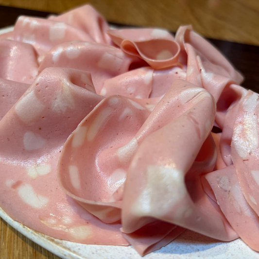 Sliced pink cured meat on a white plate