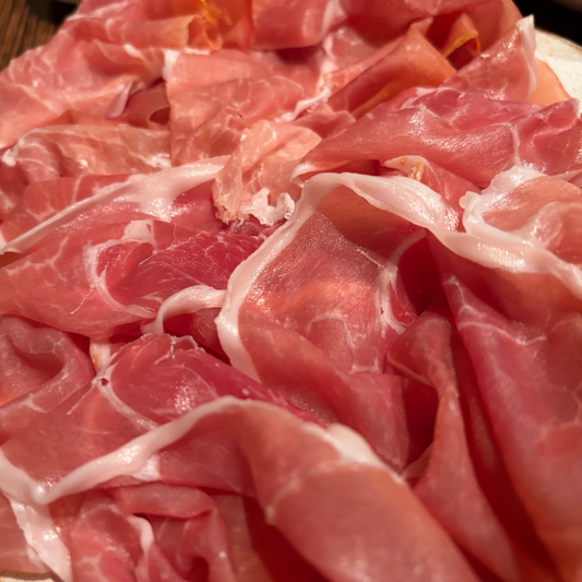 Close-up of thinly sliced meat with a pink and white color.