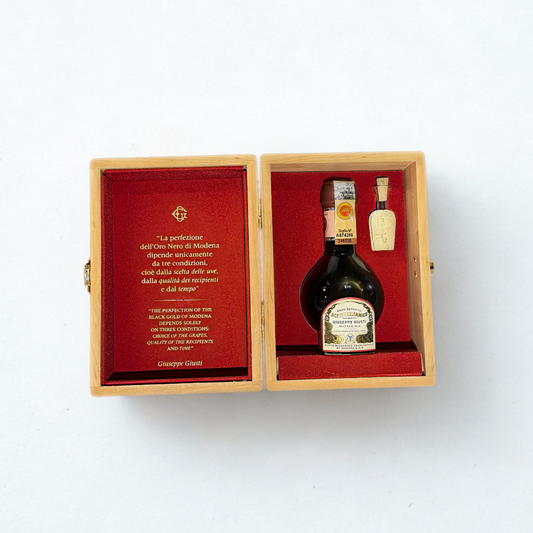 Bottle of Balsamic in a wooden box with red interior on a white background