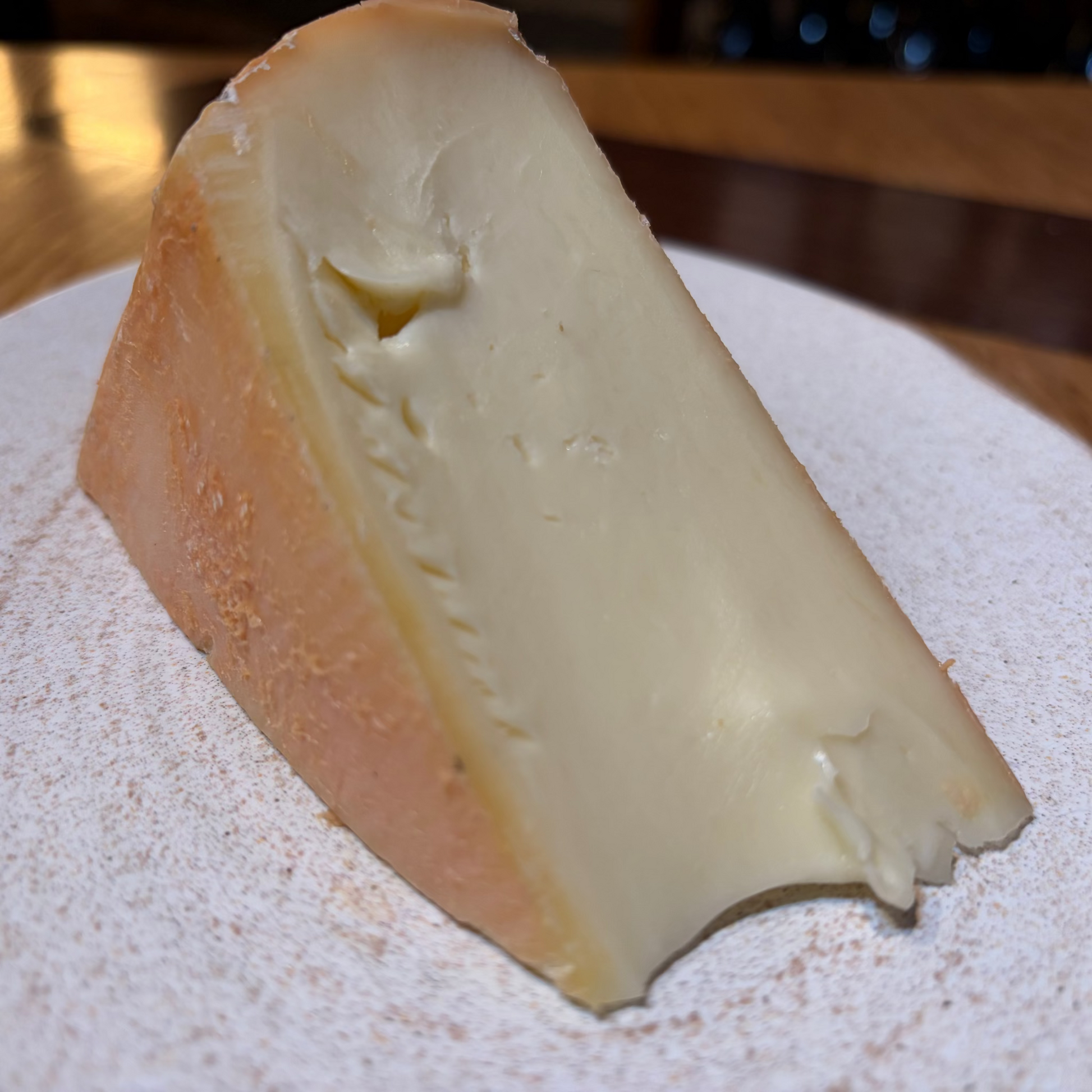 Triangular wedge of cheese on a textured surface with a blurred background