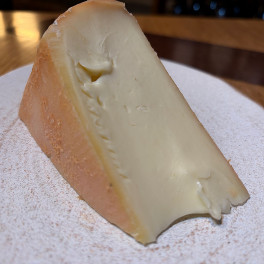 Triangular wedge of cheese on a textured surface with a blurred background