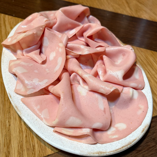 Pink sliced meat on a white plate on a wooden table