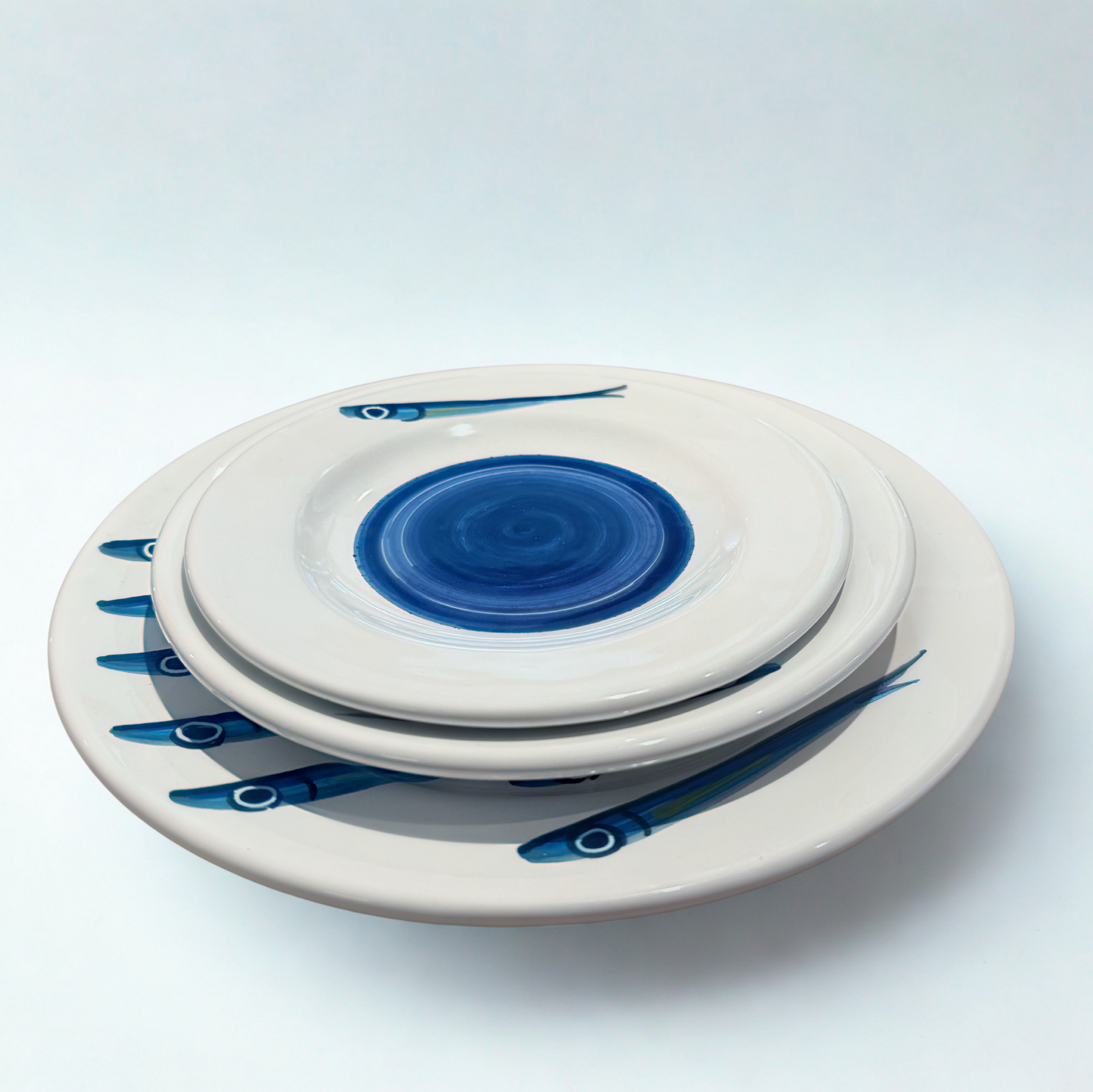 Set of ceramic plates with blue fish designs on a white background